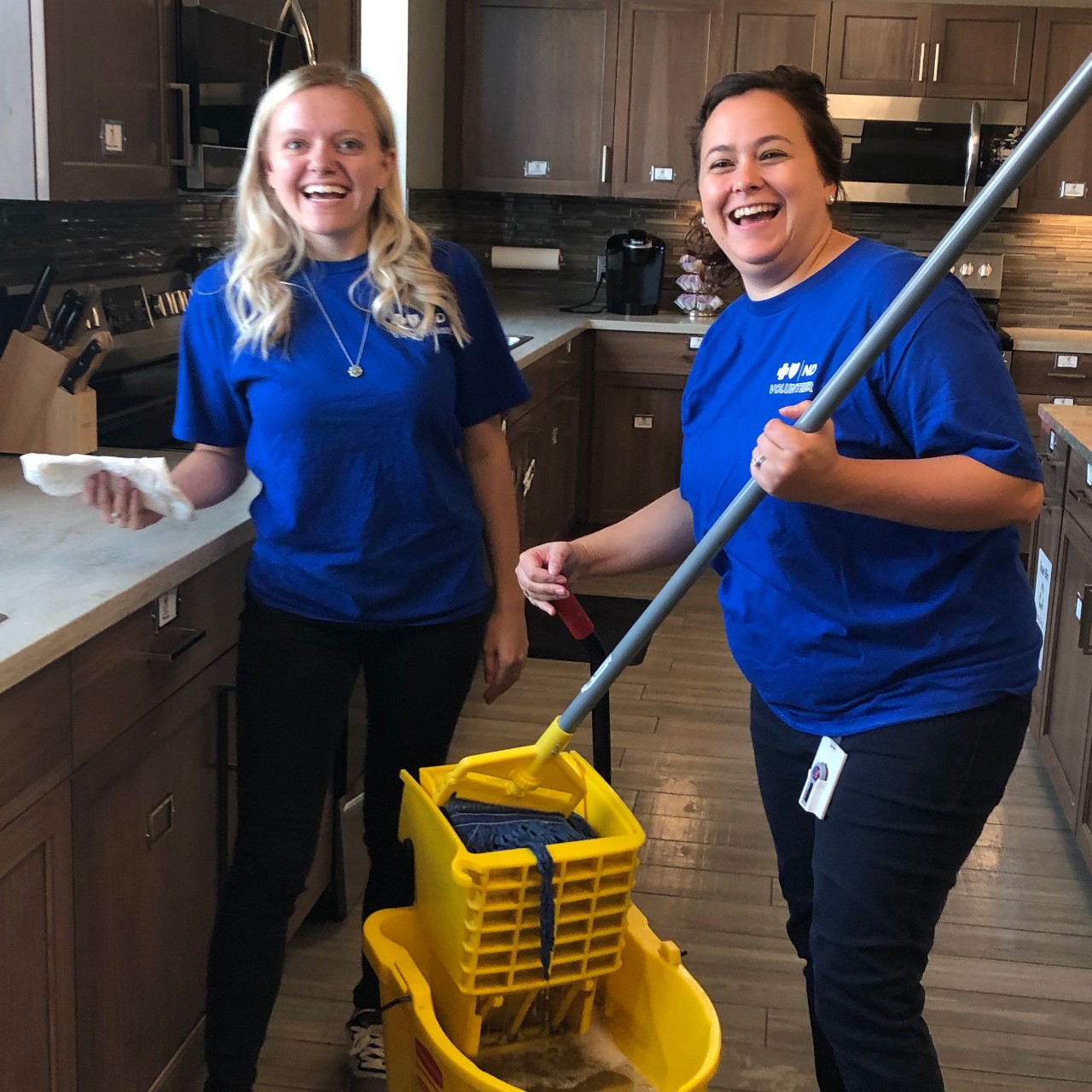 BCBSND employees volunteering, mopping floors in a kitchen at a local non-profit