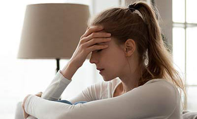 Upset woman frustrated by problem sitting on couch, embracing knees,