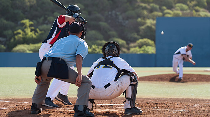 Outdoor baseball game with pitcher, hitter, catcher and umpire