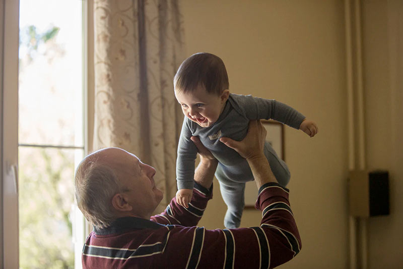 Grandfather holding smiling grandchild in the air