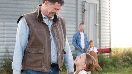 Dad and daughter smiling together outside in rural setting