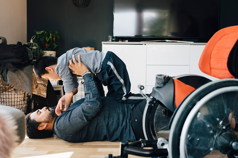 Father holding son up in the air while laying on the ground in the living room.