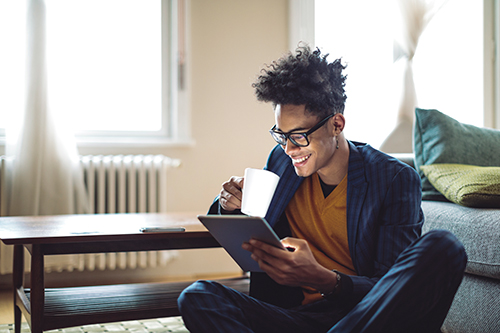 young man sitting on floor reading a tablet