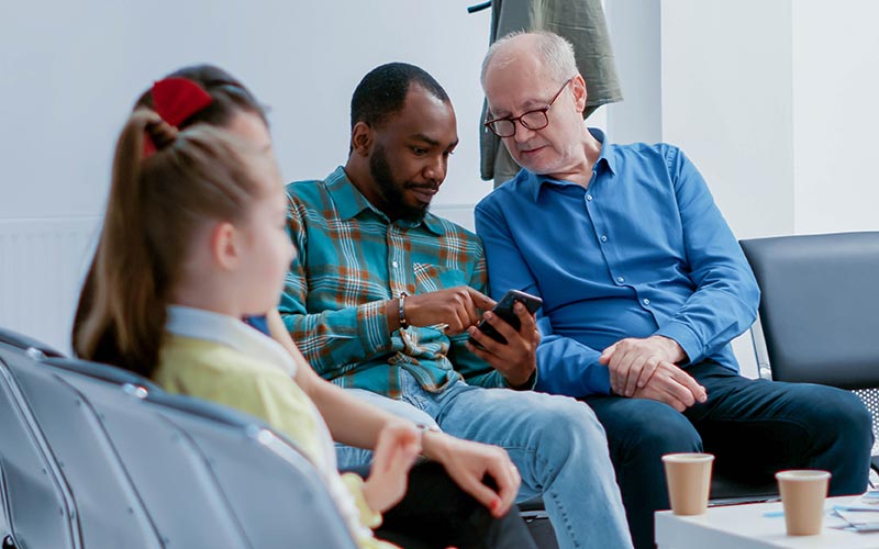 People in waiting room looking at cell phone together