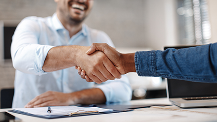 Two people shaking hands across a table