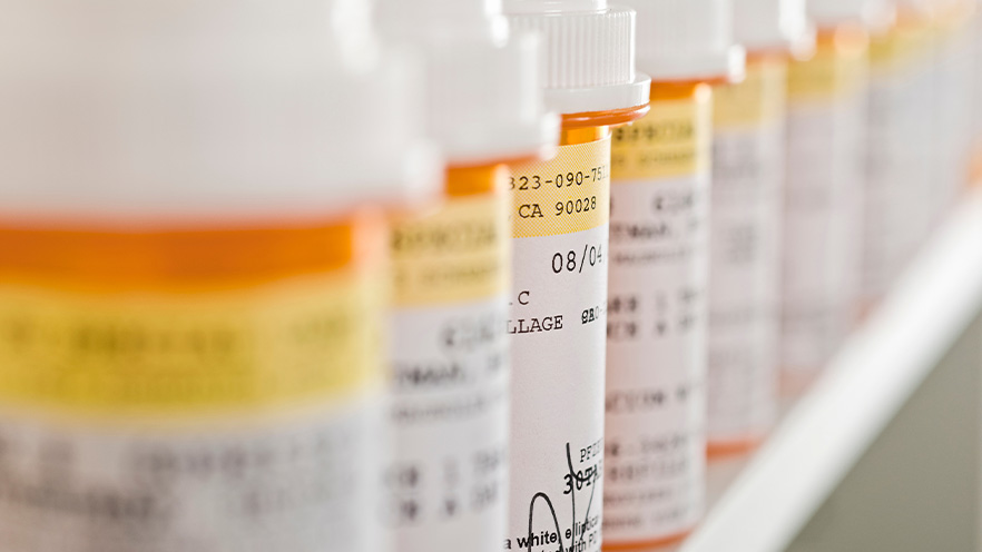 Several prescription drug bottles lined up on a shelf.