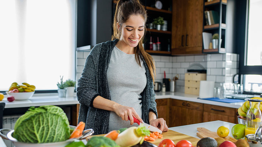 Female preparing healthy salad in kitchen.