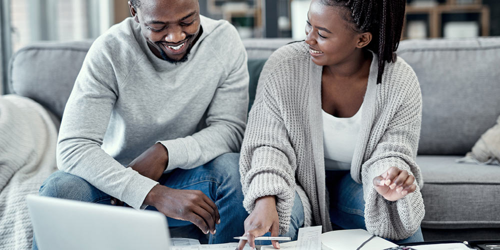 man and woman paying bills on couch at home