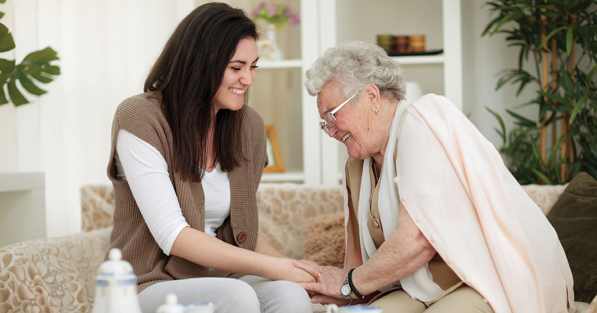 young woman visiting and laughing with elderly woman