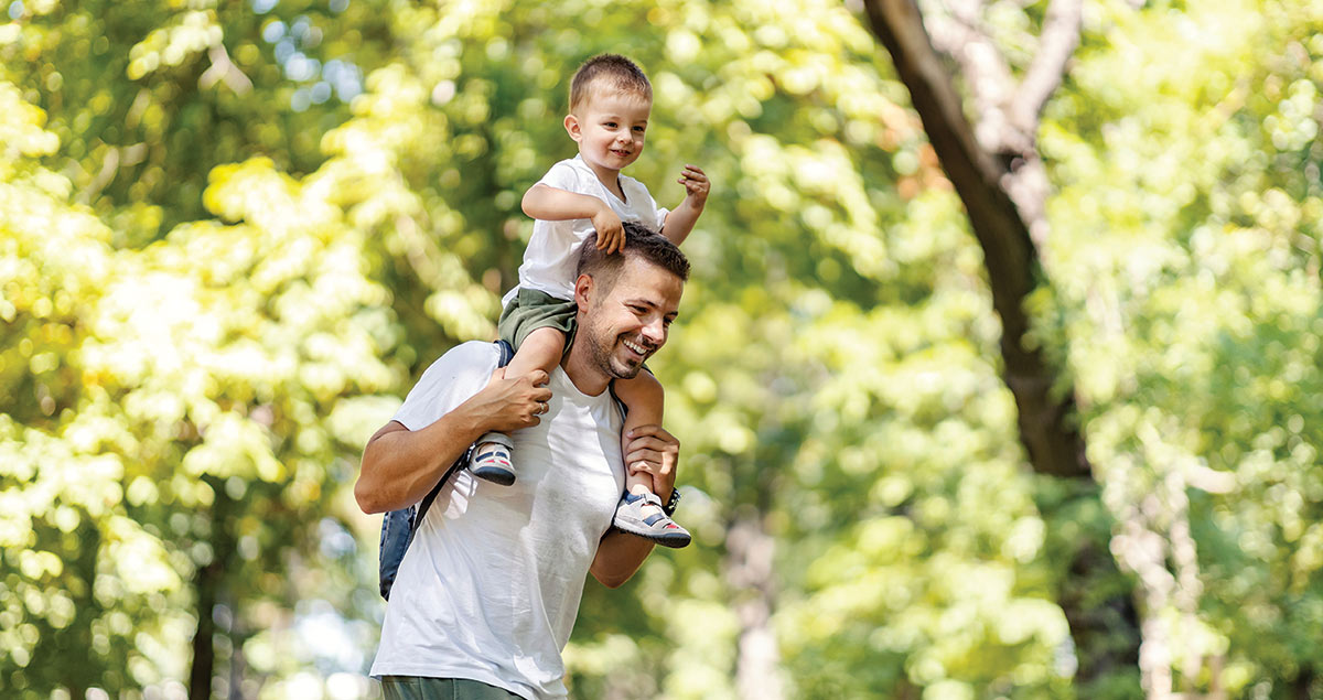 Father and son having piggyback ride and having fun in nature on earth's day.