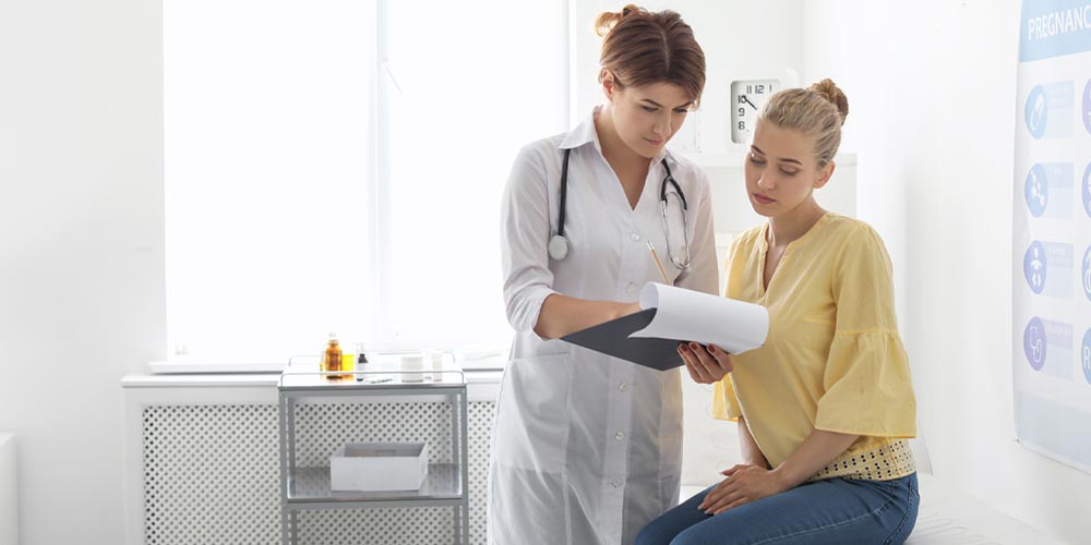 Woman in a yellow shirt consulting with a female doctor