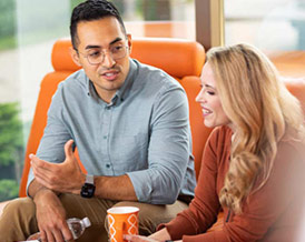 Two young professionals talking on a sofa.