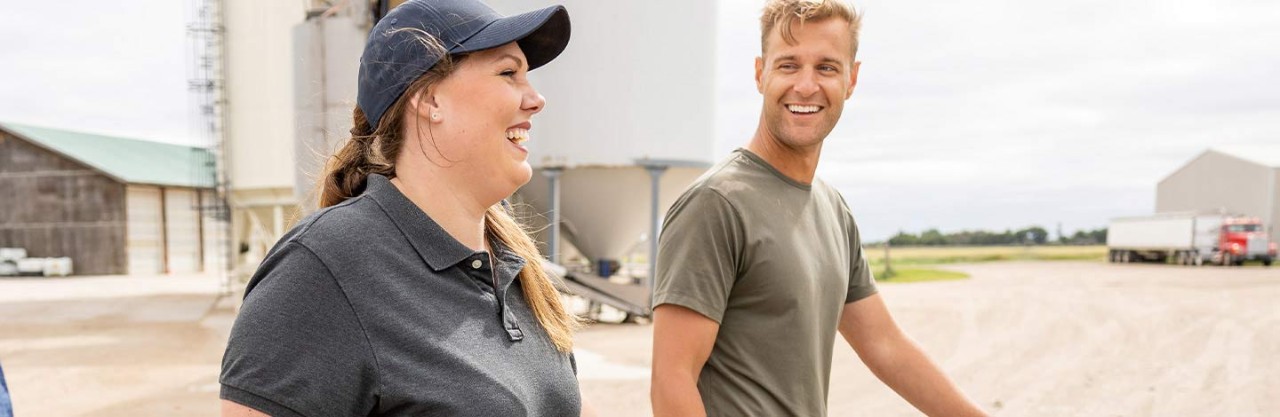 Man and woman walking and smiling on a farm lot.
