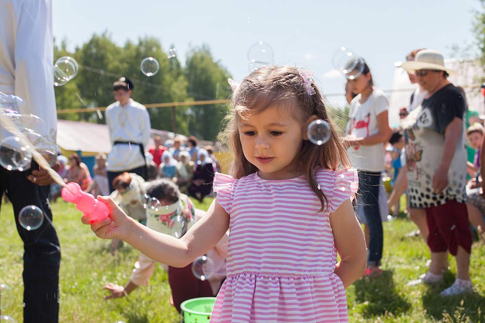 Little girl plays with soap bubbles at a holiday
