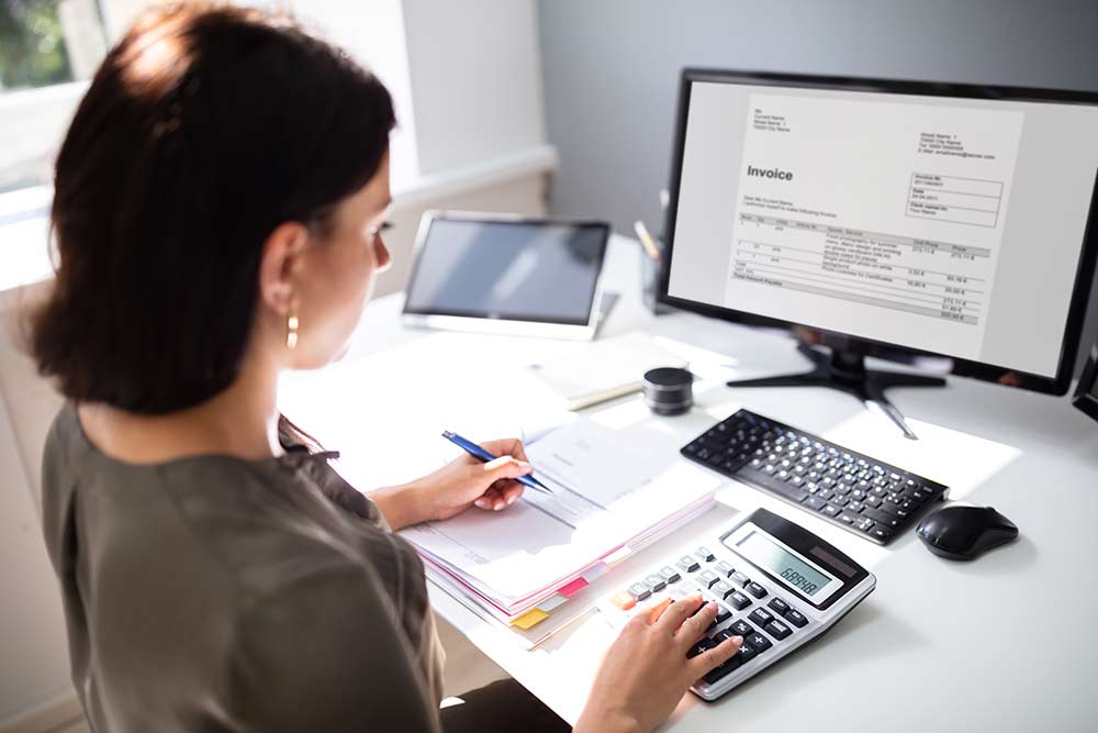 Woman using computer and calculator to pay bills