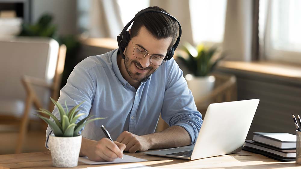 Smiling Caucasian man in headphones study on laptop