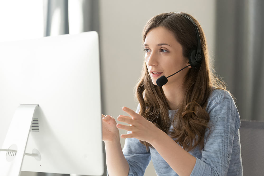 Serious female call center operator in headset talking with customer