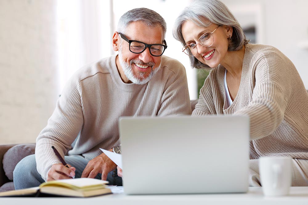 mature couple looking at a laptop and taking notes
