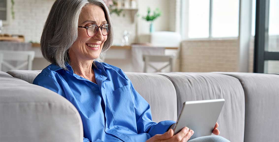 Smiling Medicare aged woman looking at a tablet