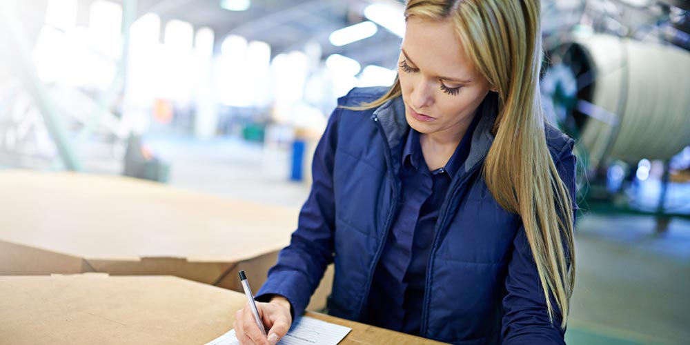 Professional woman writing with a pen in an industrial setting