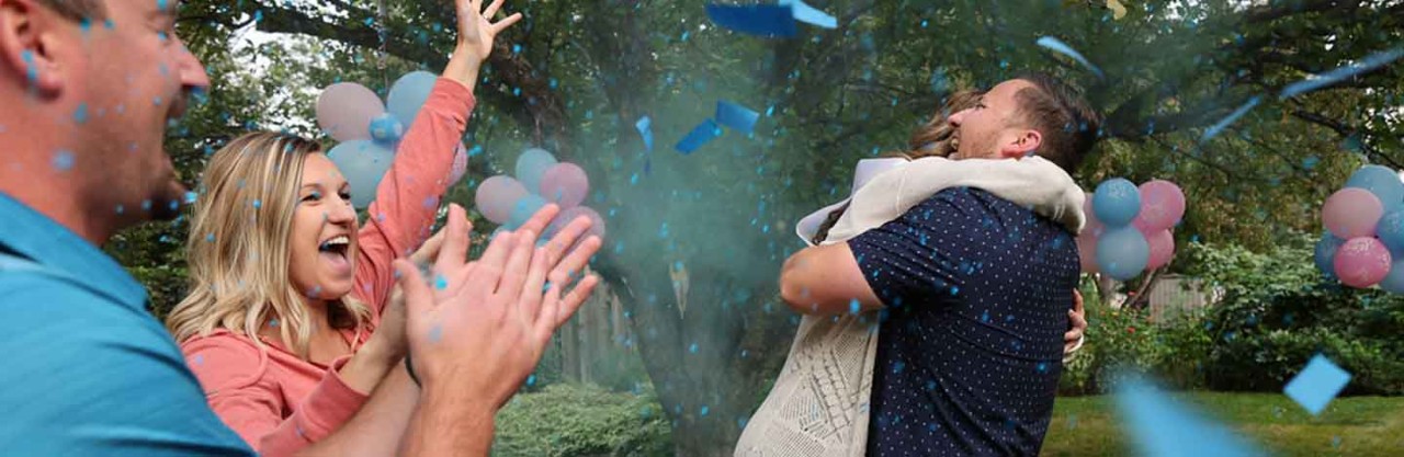 Couple celebrates gender reveal with family in backyard.
