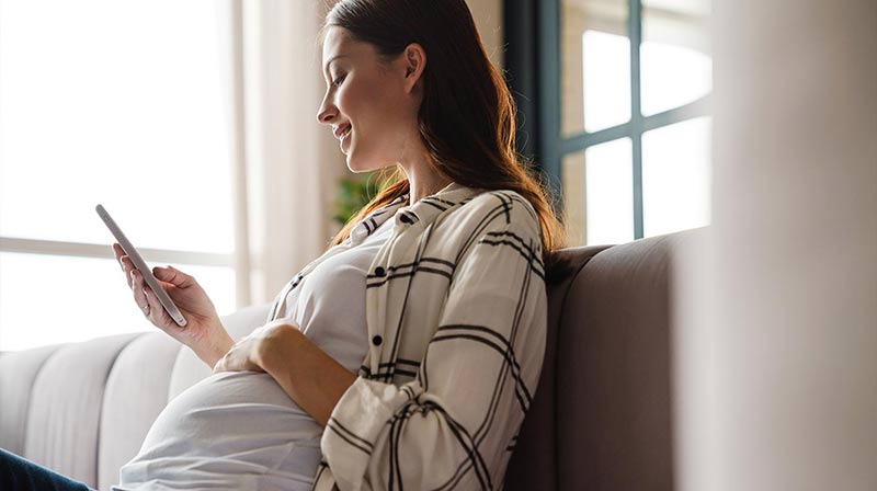 Smiling pregnant woman using a smart phone