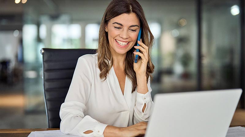 Smiling woman in office talking on a smart phone