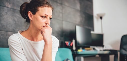 Sad woman sitting on a sofa in the living room