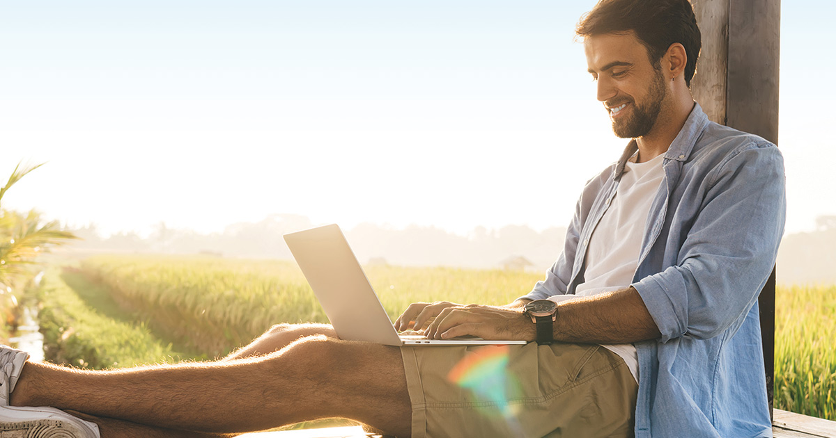 Happy man with laptop working remotely on terrace