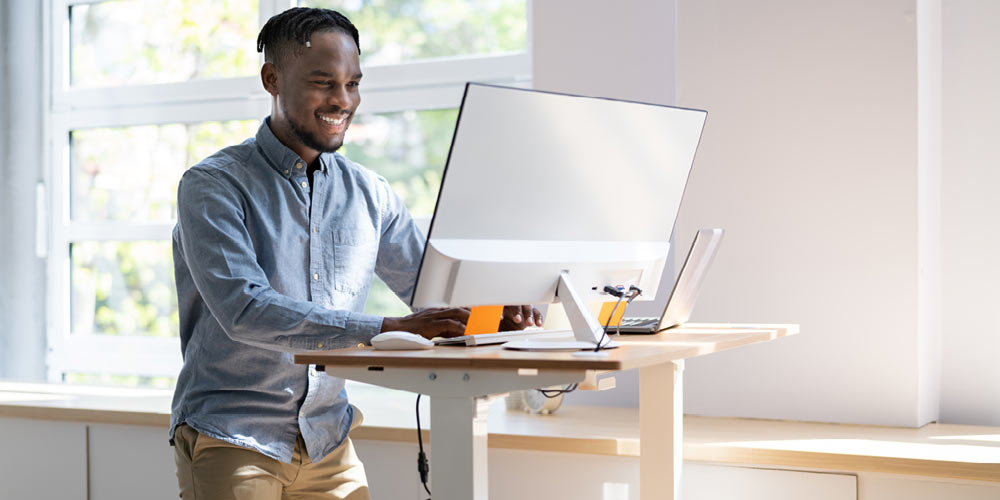 African American man using a standing desk to work at a computer