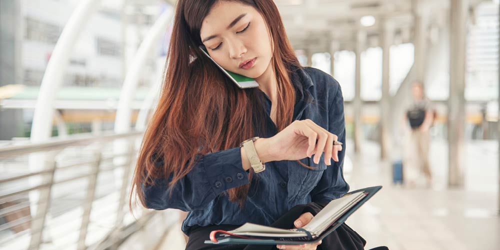 woman looking at her watch and holding a planner