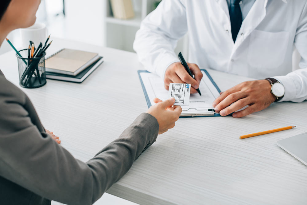 A member showing her insurance ID card to a doctor