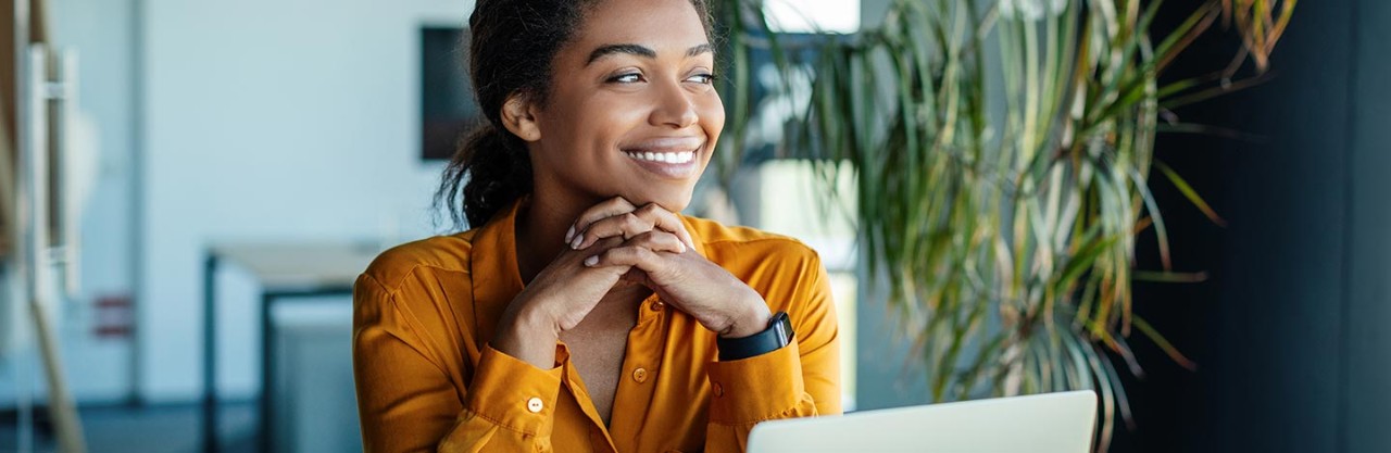 A smiling woman sitting at a laptop