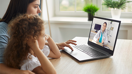 Mother and daughter using laptop to visit virtually with doctor 