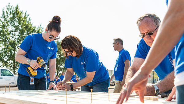 Employees working outdoors with tools on a volunteer project