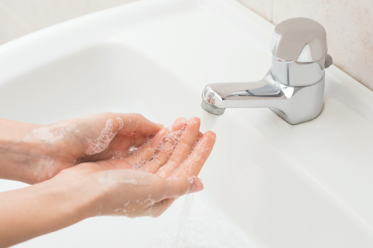 Closeup shot of a woman washing hands with soap lather over bathroom sink. Girl cleaning hand.