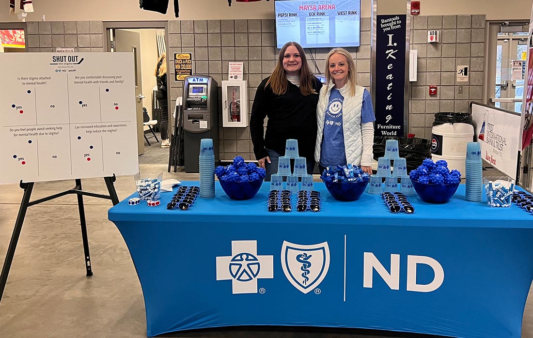 Two employees at the BCBSND booth at the Minot Minotauros Hockey Game.