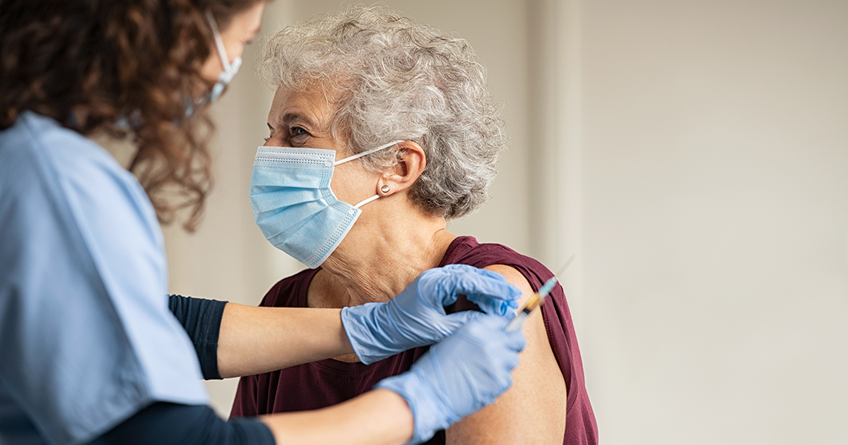 General practitioner vaccinating old patient in private clinic with copy space. Doctor giving injection to senior woman at hospital. Nurse holding syringe and using cotton before make Covid-19 or coronavirus vaccine.