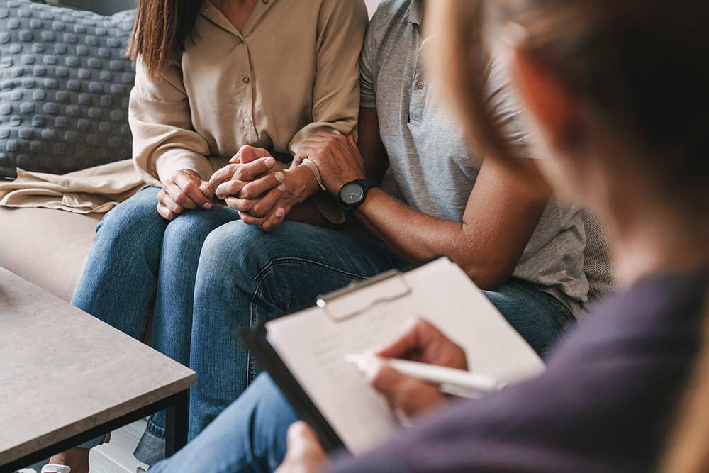 casual nice couple having conversation with psychologist on therapy session in room