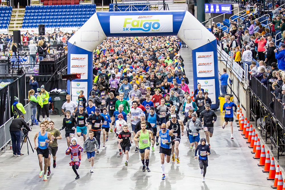 Fargo Marathon Friday Night 5K participants cross starting line in FargoDome.