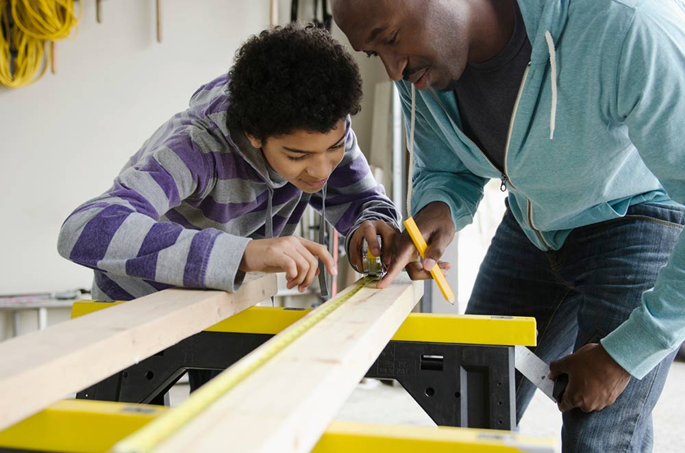 father teaching son how to use tools