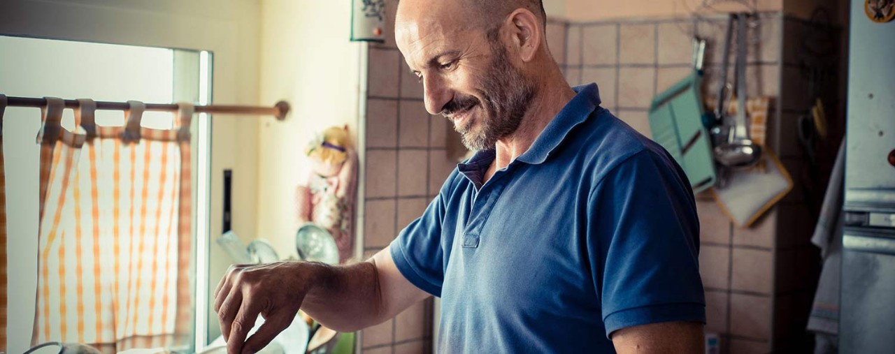 Middle-aged man stirring a pot of chili in his kitchen.