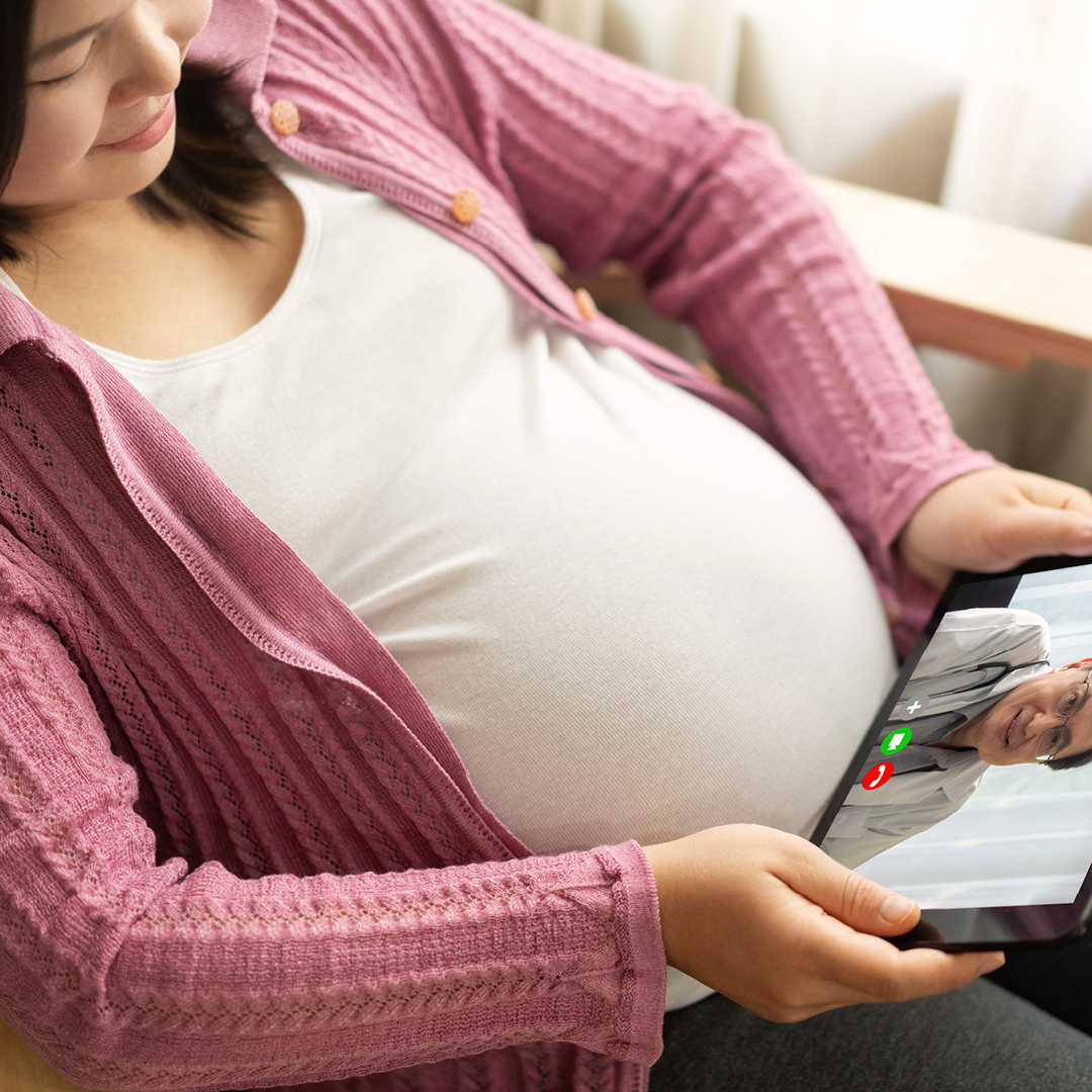 Pregnant woman visiting with doctor on tablet