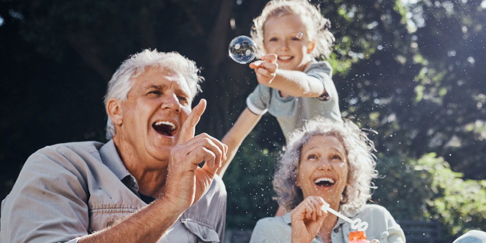 Smiling grandparents blowing bubbles with granddaughter