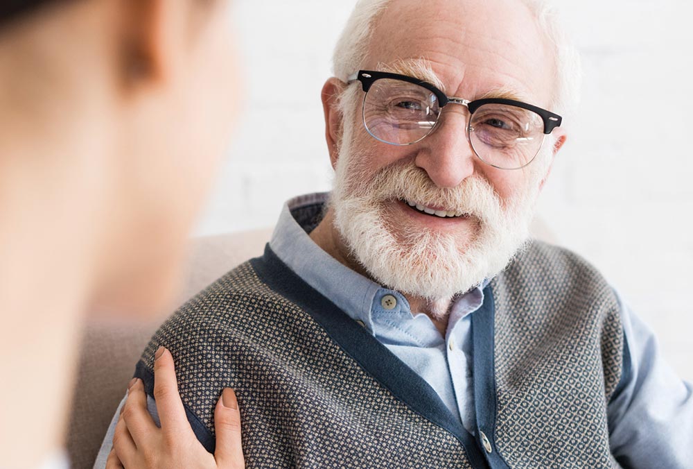 Selective focus of happy grey haired man looking at nurse