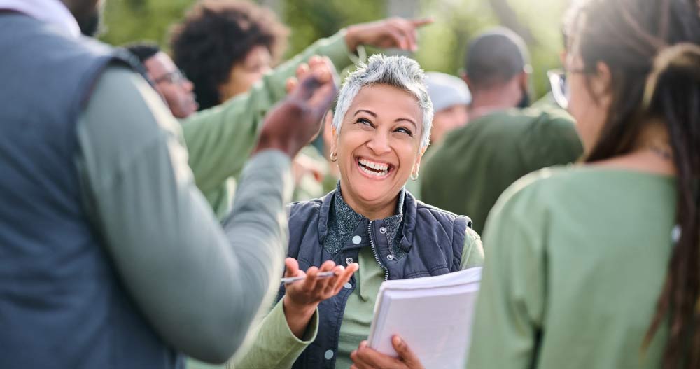 Woman in crowd of people smiles while talking to other people in the crowd.