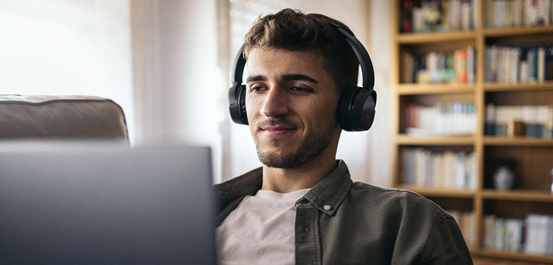 A man at home wearing headphones and using a laptop