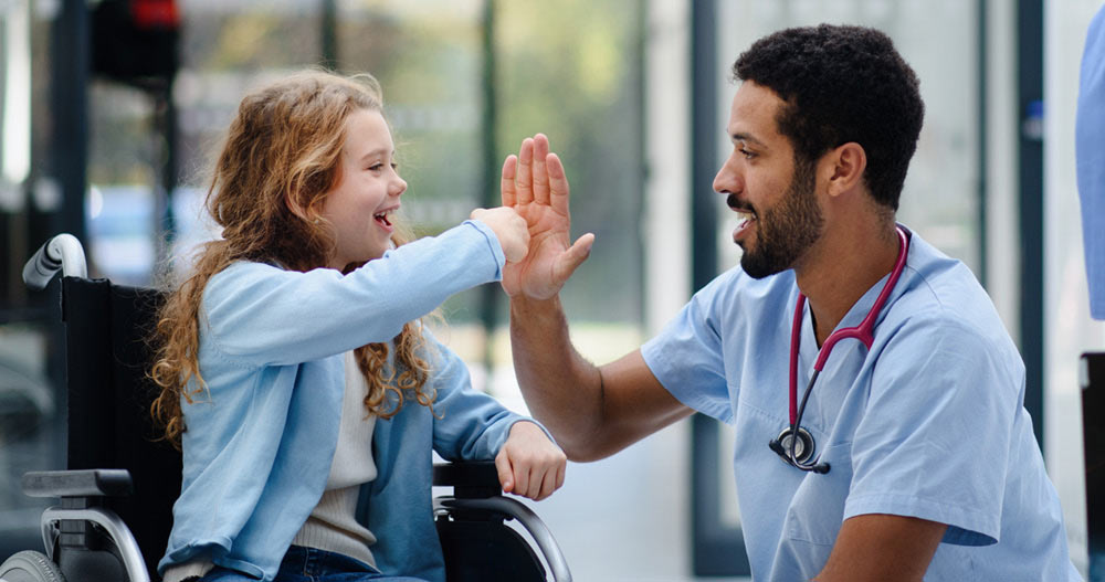 child in a wheelchair giving a high five to a doctor
